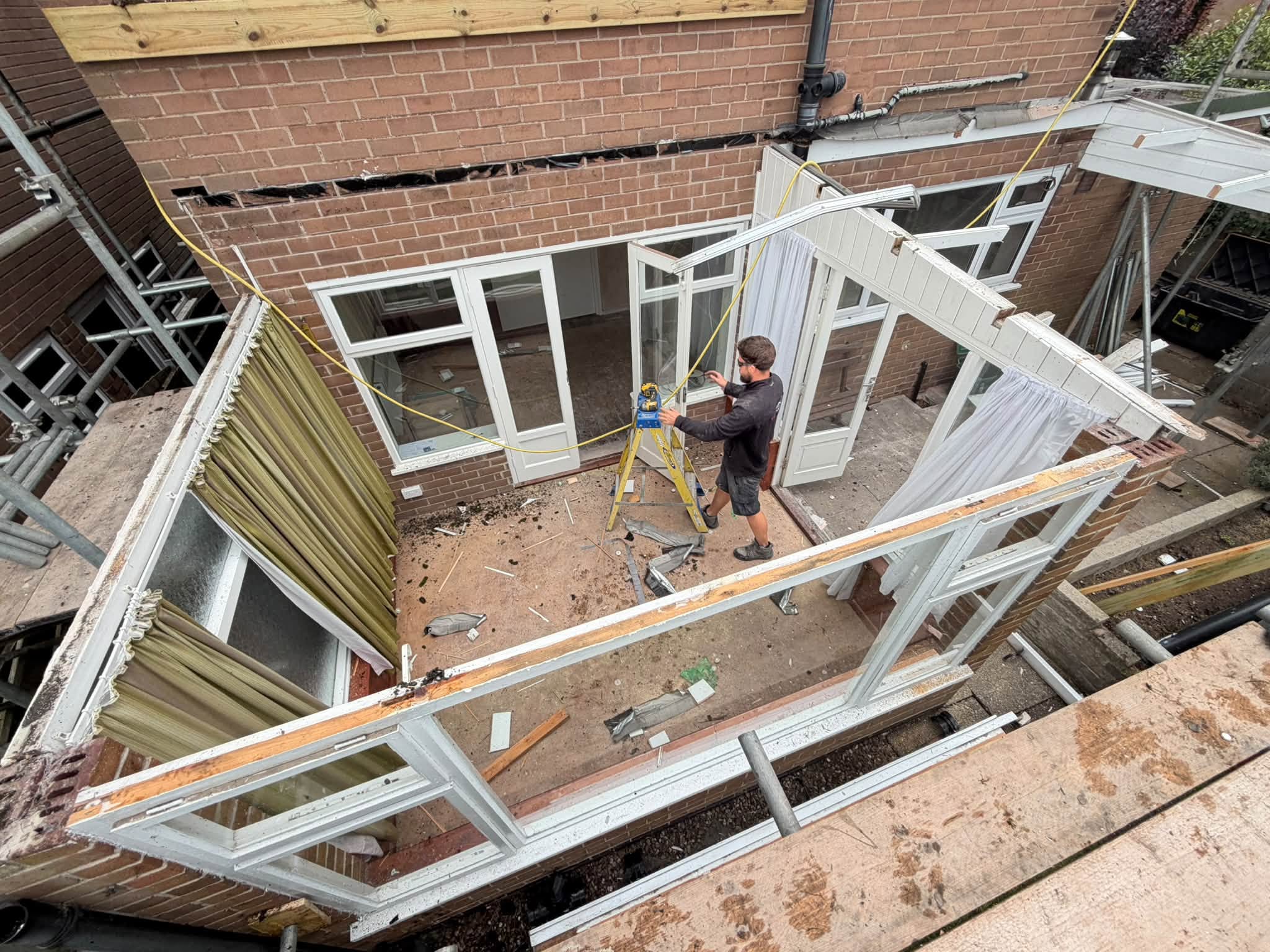 An old conservatory roof stripped back to its frame, a worker below